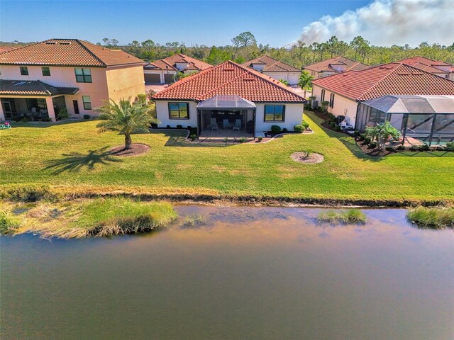 rear view of property featuring glass enclosure, a yard, and a water view