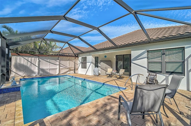 view of pool with glass enclosure and a patio