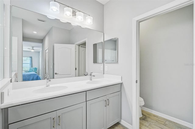 bathroom with toilet, vanity, ceiling fan, and wood-type flooring