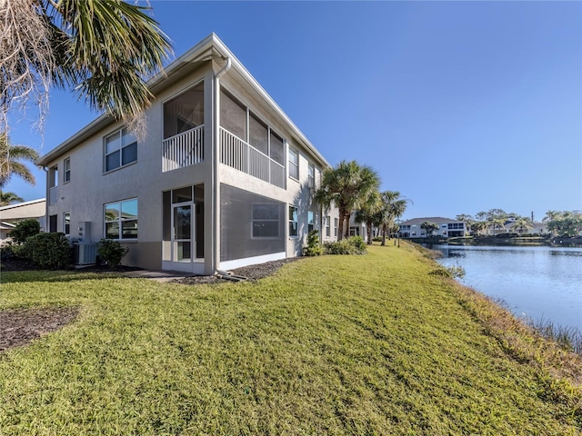 view of side of home with a yard, a water view, and central AC