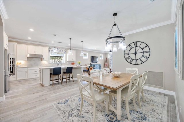 dining area featuring light hardwood / wood-style floors and crown molding