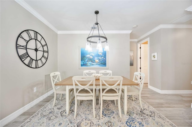 dining area with light hardwood / wood-style floors, ornamental molding, and a chandelier