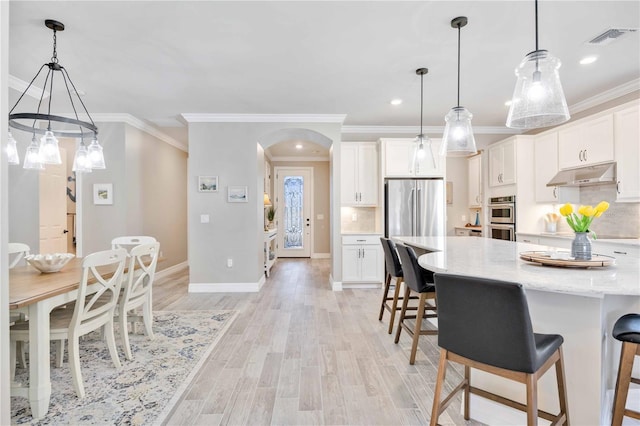 kitchen featuring stainless steel appliances, crown molding, pendant lighting, decorative backsplash, and white cabinets