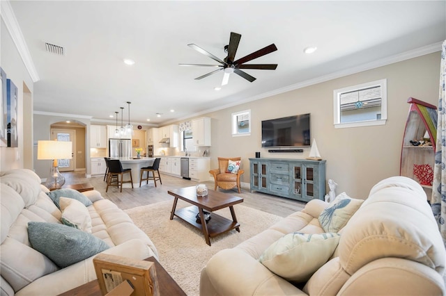 living room with crown molding, ceiling fan, and light wood-type flooring