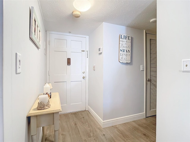 doorway featuring a textured ceiling and light hardwood / wood-style flooring