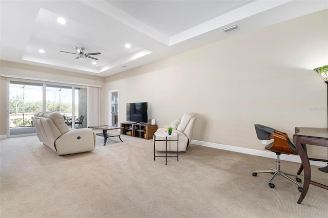 living room featuring light carpet, ceiling fan, and a tray ceiling