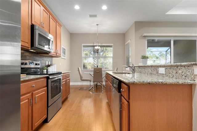 kitchen with stainless steel appliances, decorative light fixtures, tasteful backsplash, and a wealth of natural light