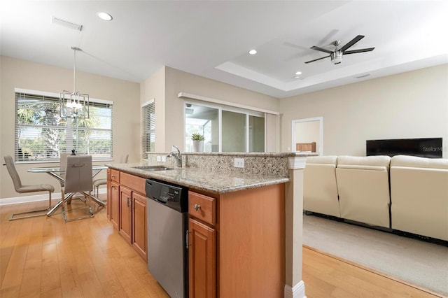 kitchen with sink, an island with sink, stainless steel dishwasher, hanging light fixtures, and light stone countertops