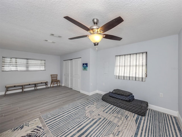 unfurnished bedroom featuring light wood-type flooring, a textured ceiling, a closet, and ceiling fan