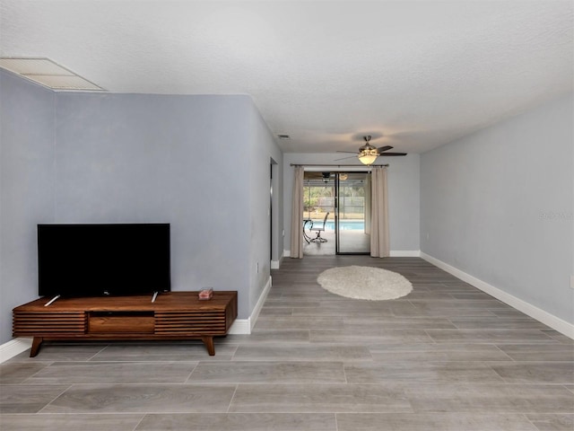 living room with ceiling fan and a textured ceiling