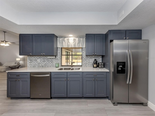 kitchen featuring sink, ceiling fan, decorative backsplash, a textured ceiling, and stainless steel appliances