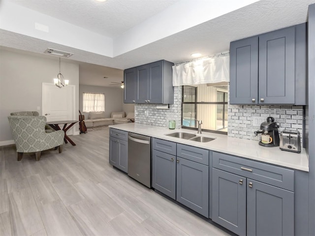 kitchen featuring sink, stainless steel dishwasher, decorative backsplash, a textured ceiling, and decorative light fixtures