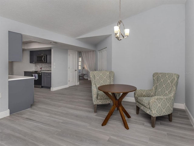 living area with light wood-type flooring, vaulted ceiling, and an inviting chandelier