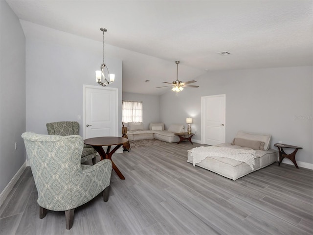 interior space featuring ceiling fan with notable chandelier, wood-type flooring, and vaulted ceiling