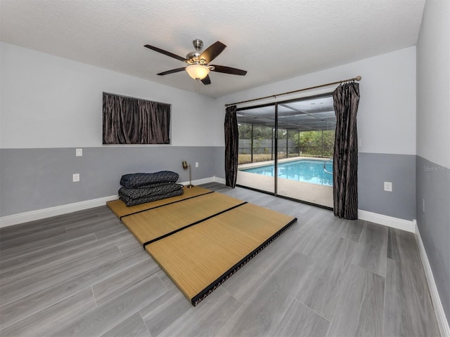 interior space with hardwood / wood-style floors, a textured ceiling, a pool, and ceiling fan