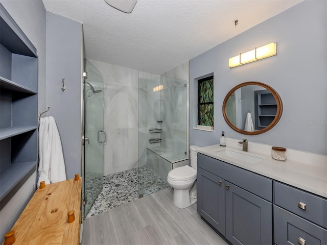 bathroom featuring an enclosed shower, vanity, a textured ceiling, wood-type flooring, and toilet