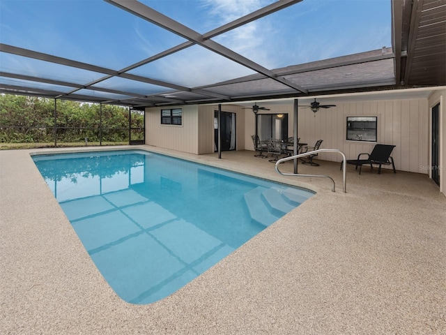 view of swimming pool with ceiling fan, a patio area, and glass enclosure