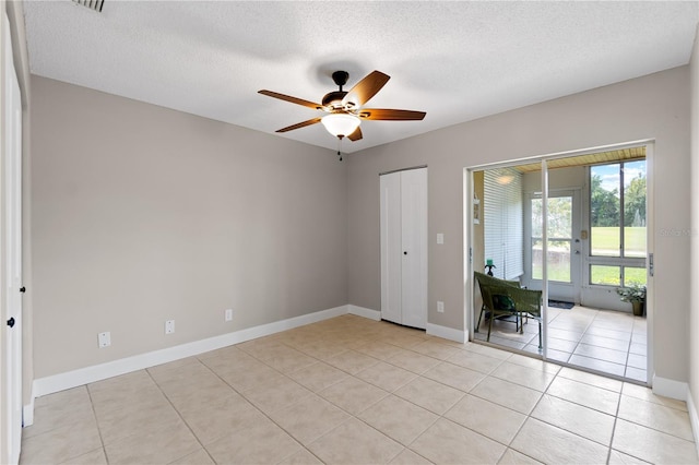 unfurnished bedroom featuring ceiling fan, light tile patterned floors, and a textured ceiling