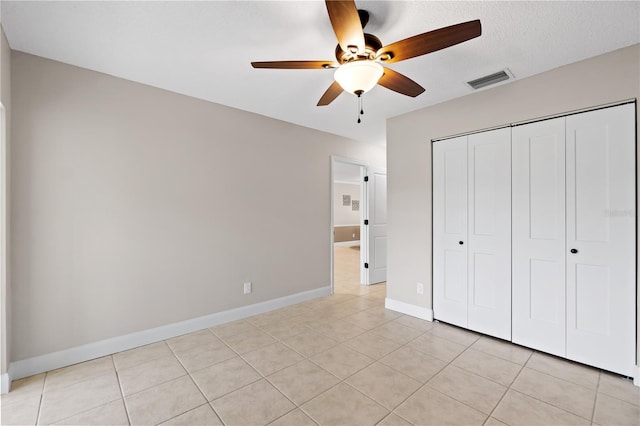 unfurnished bedroom featuring ceiling fan, light tile patterned flooring, and a closet