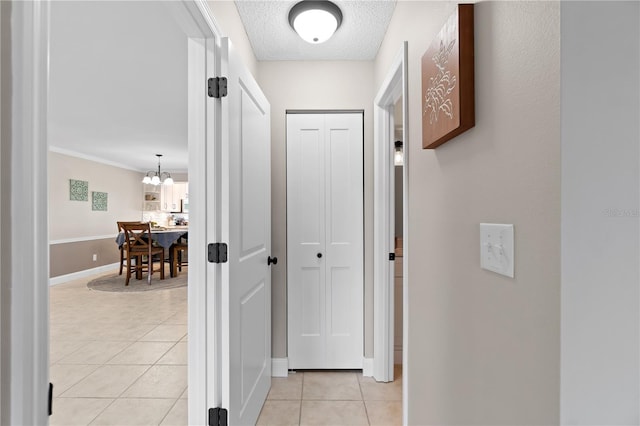 hallway featuring light tile patterned floors, a chandelier, and a textured ceiling