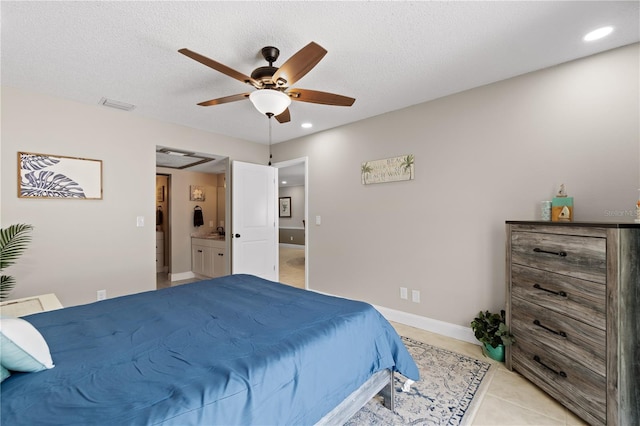 bedroom featuring ceiling fan, light tile patterned flooring, ensuite bathroom, and a textured ceiling