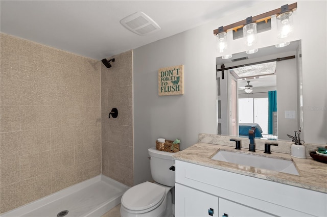 bathroom featuring tiled shower, ceiling fan, vanity, and toilet