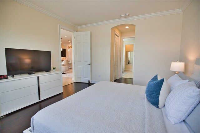 bedroom with dark hardwood / wood-style flooring, crown molding, and connected bathroom