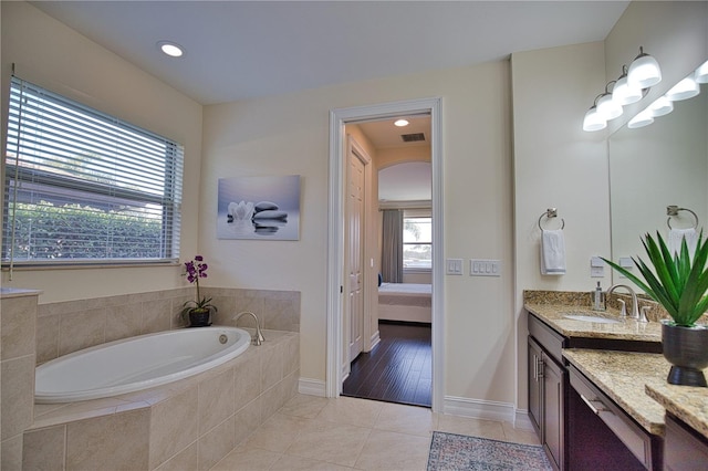 bathroom with tiled bath, tile patterned flooring, and vanity