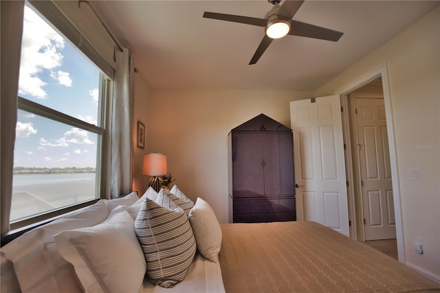 bedroom featuring ceiling fan and a water view