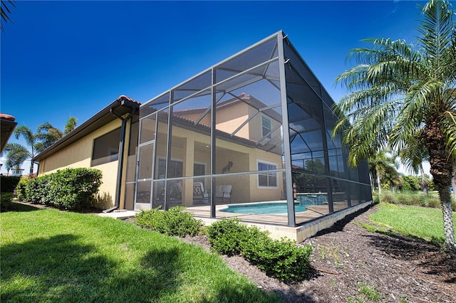 rear view of property with a lawn, glass enclosure, and a patio