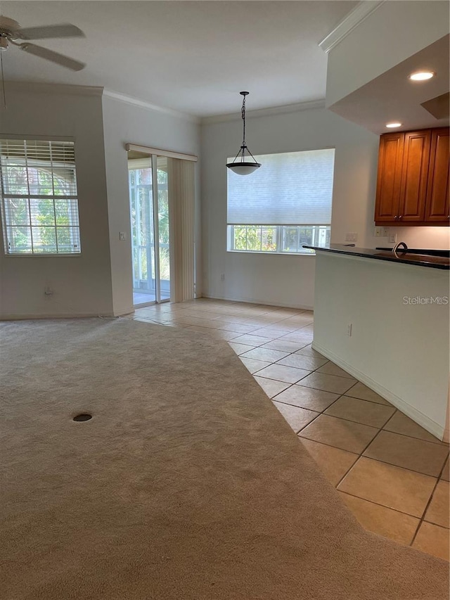 unfurnished dining area with light tile patterned floors, a wealth of natural light, crown molding, and ceiling fan