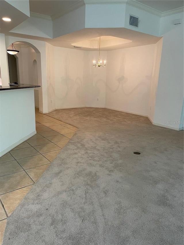 tiled spare room featuring ornamental molding and a notable chandelier