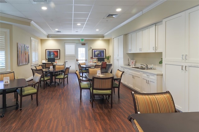 dining area with a paneled ceiling, dark hardwood / wood-style floors, crown molding, and sink