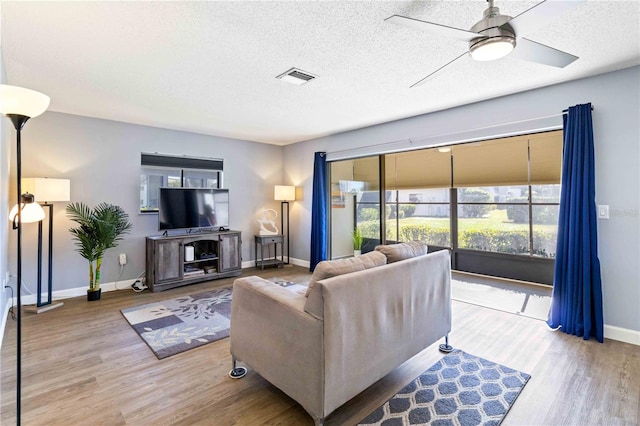 living room with ceiling fan, wood-type flooring, and a textured ceiling