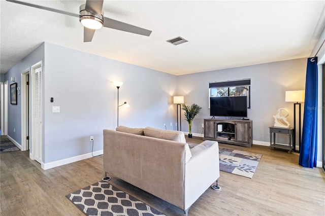 living room with ceiling fan, light hardwood / wood-style floors, and a textured ceiling