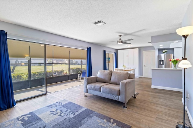 living room featuring hardwood / wood-style floors, ceiling fan, and a textured ceiling