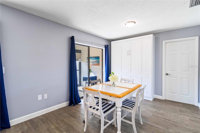 dining room featuring a textured ceiling and dark wood-type flooring