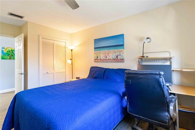 bedroom featuring ceiling fan, a closet, wood-type flooring, and a textured ceiling