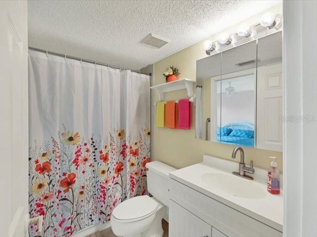 bathroom featuring toilet, vanity, walk in shower, and a textured ceiling