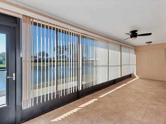 unfurnished sunroom with ceiling fan, a water view, and plenty of natural light