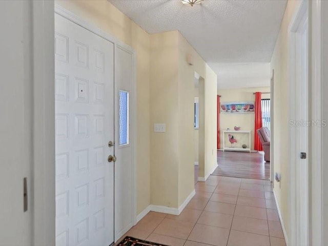 foyer entrance with a textured ceiling and light tile patterned flooring