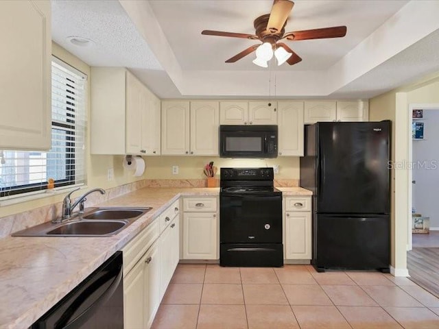 kitchen featuring ceiling fan, black appliances, a raised ceiling, sink, and light tile patterned floors