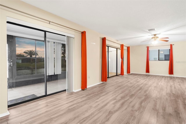 spare room featuring light wood-type flooring, ceiling fan, and a textured ceiling