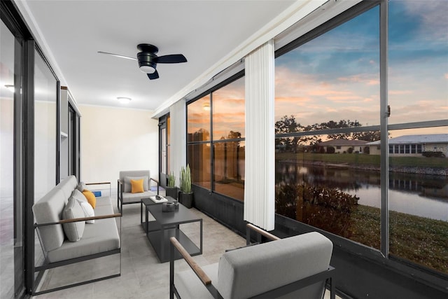 sunroom featuring ceiling fan and a water view