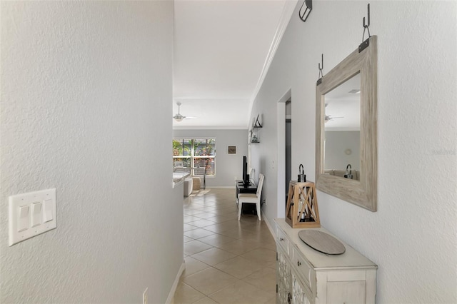 hall featuring light tile patterned floors and crown molding