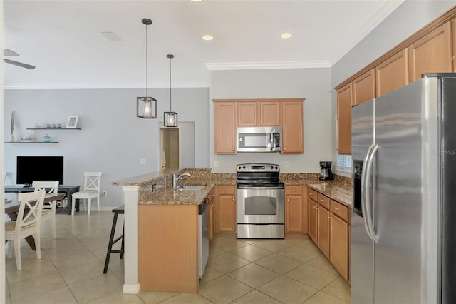 kitchen featuring a kitchen bar, appliances with stainless steel finishes, kitchen peninsula, sink, and decorative light fixtures