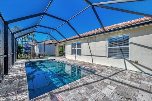 view of pool featuring glass enclosure and a patio