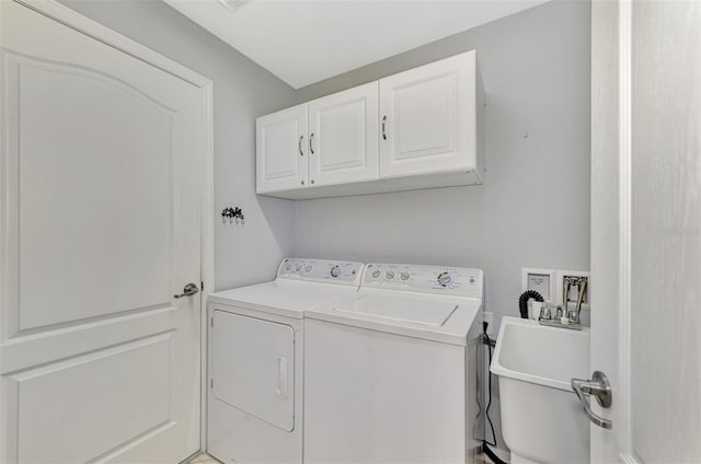 clothes washing area featuring cabinets, washing machine and dryer, and sink