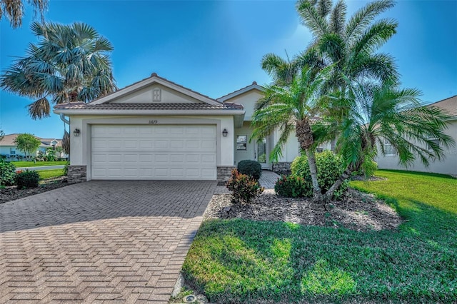 11679 Anhinga Ave, Venice, FL 34292 - view of front of home featuring stucco siding, decorative driveway, stone siding, and a front yard