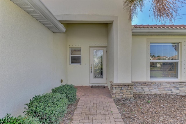 11679 Anhinga Ave, Venice, FL 34292 - view of exterior entry featuring a tiled roof, stucco siding, and stone siding